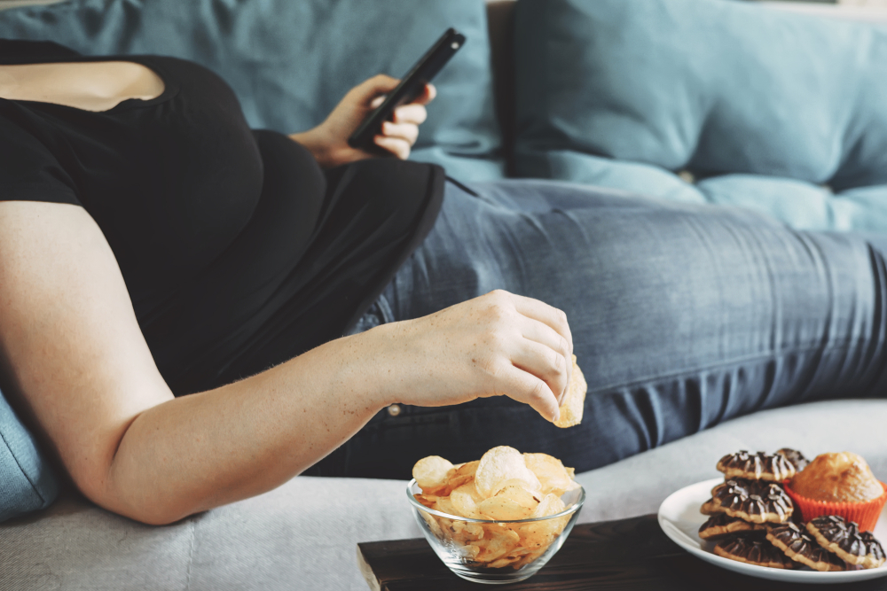 overweight person on couch eating chips