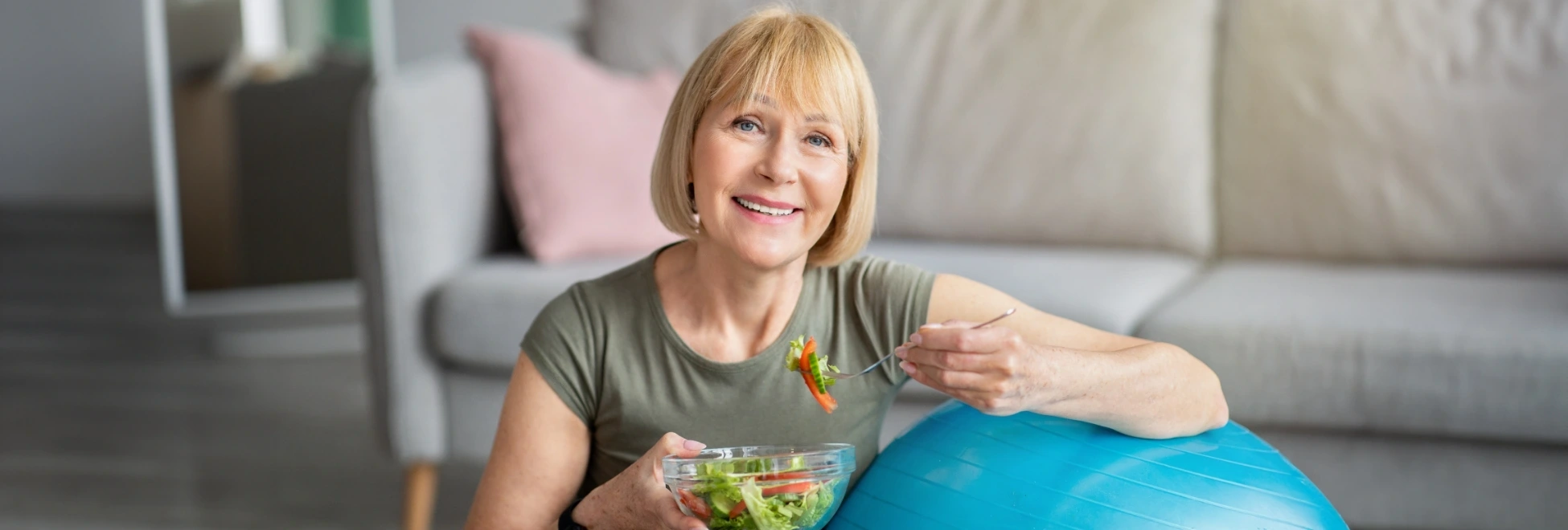 senior woman sitting next to exercise ball eating healthy