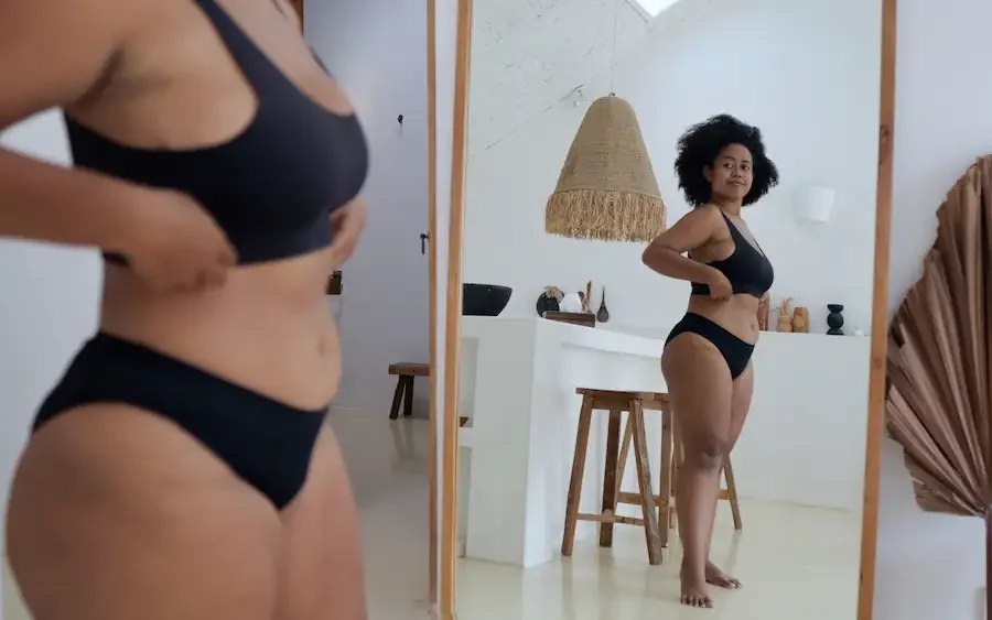 woman looking in the mirror at hear weight loss progress