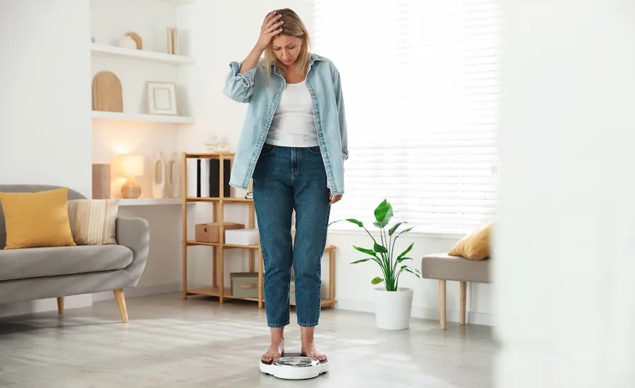 woman standing on scale unhappy with weight gain